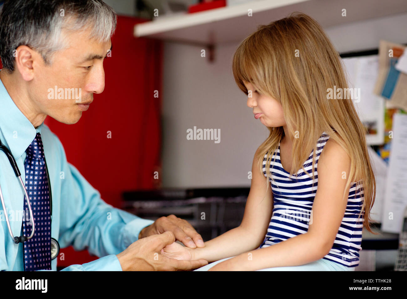 Arzt untersuchen Mädchen, während ihre Hand zu Hause Holding Stockfoto