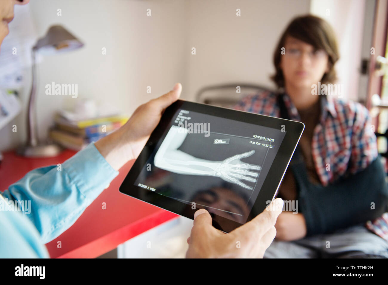 Zugeschnittenes Bild der Arzt prüft Hand X-ray mit Junge im Hintergrund sitzen Stockfoto