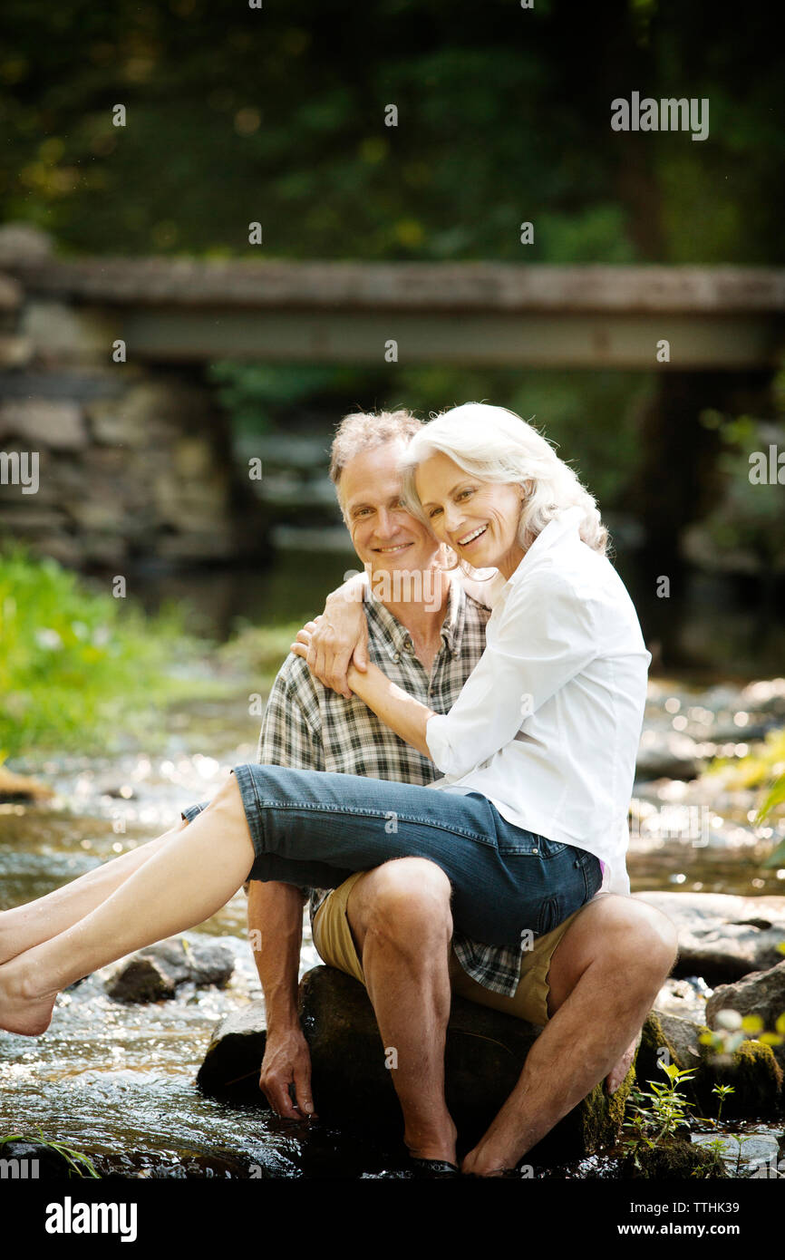 Portrait von gerne ältere Frau sitzt auf dem Schoß der Mann im Stream Stockfoto