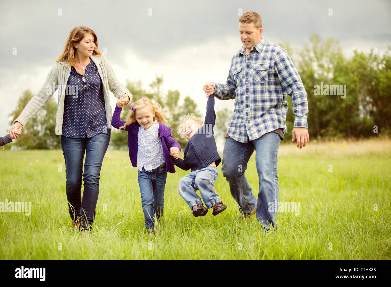 Glückliche Kinder mit Eltern genießen auf der Wiese Stockfoto