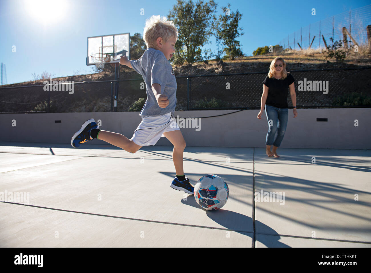 Junge kicking Ball beim Fußball spielen mit Mutter Stockfoto