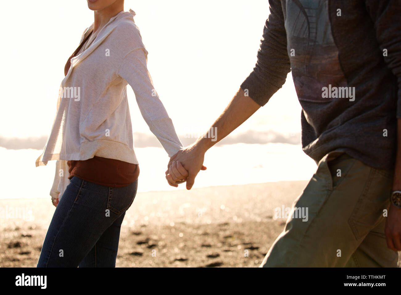 Paar Hände halten beim Spaziergang am Strand. Stockfoto