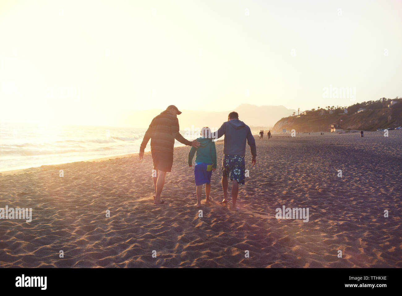 Ansicht der Rückseite des Familie Wandern am Strand gegen den klaren Himmel bei Sonnenuntergang Stockfoto