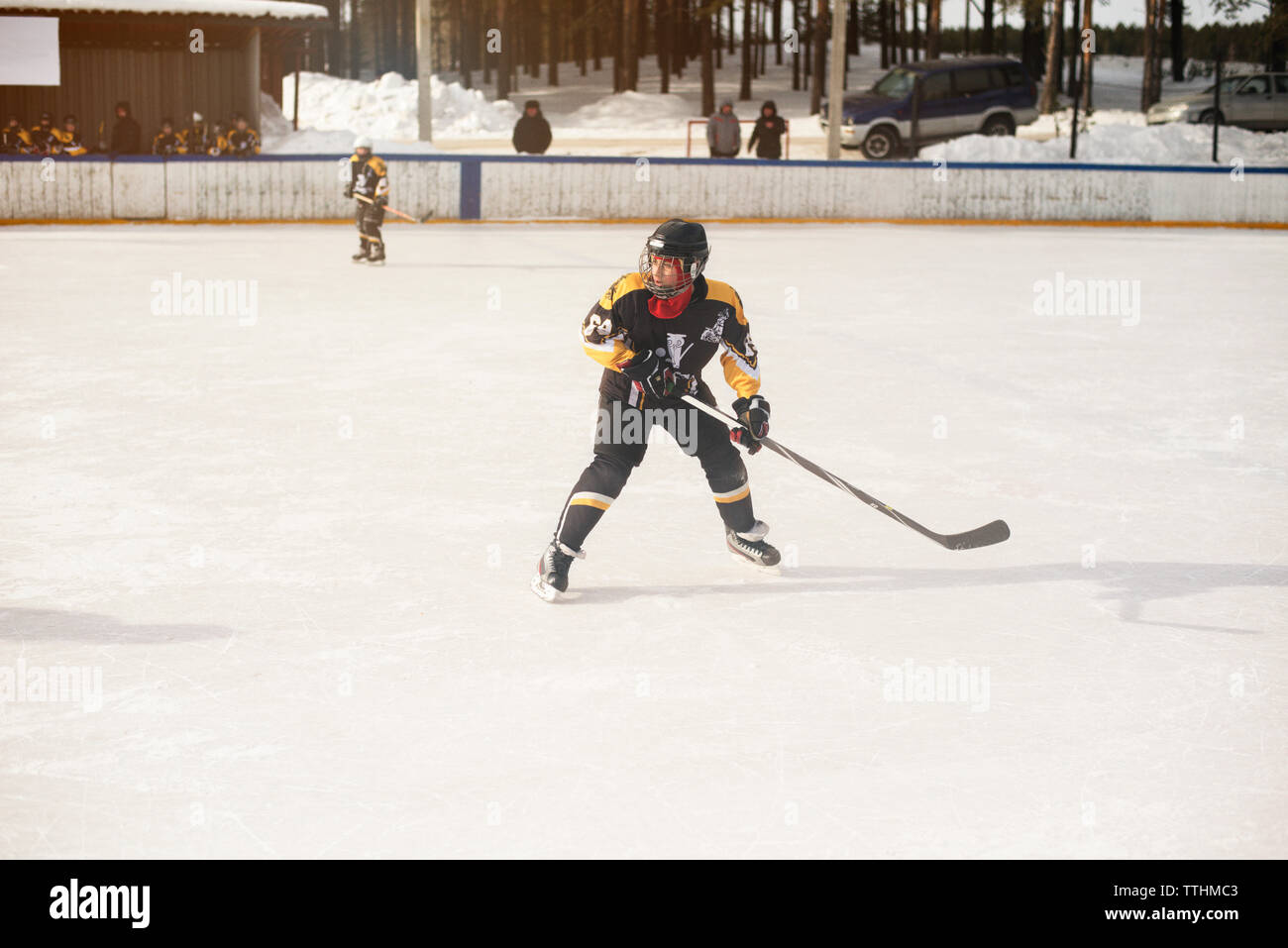 Junge spielt Eishockey während der sonnigen Tag Stockfoto