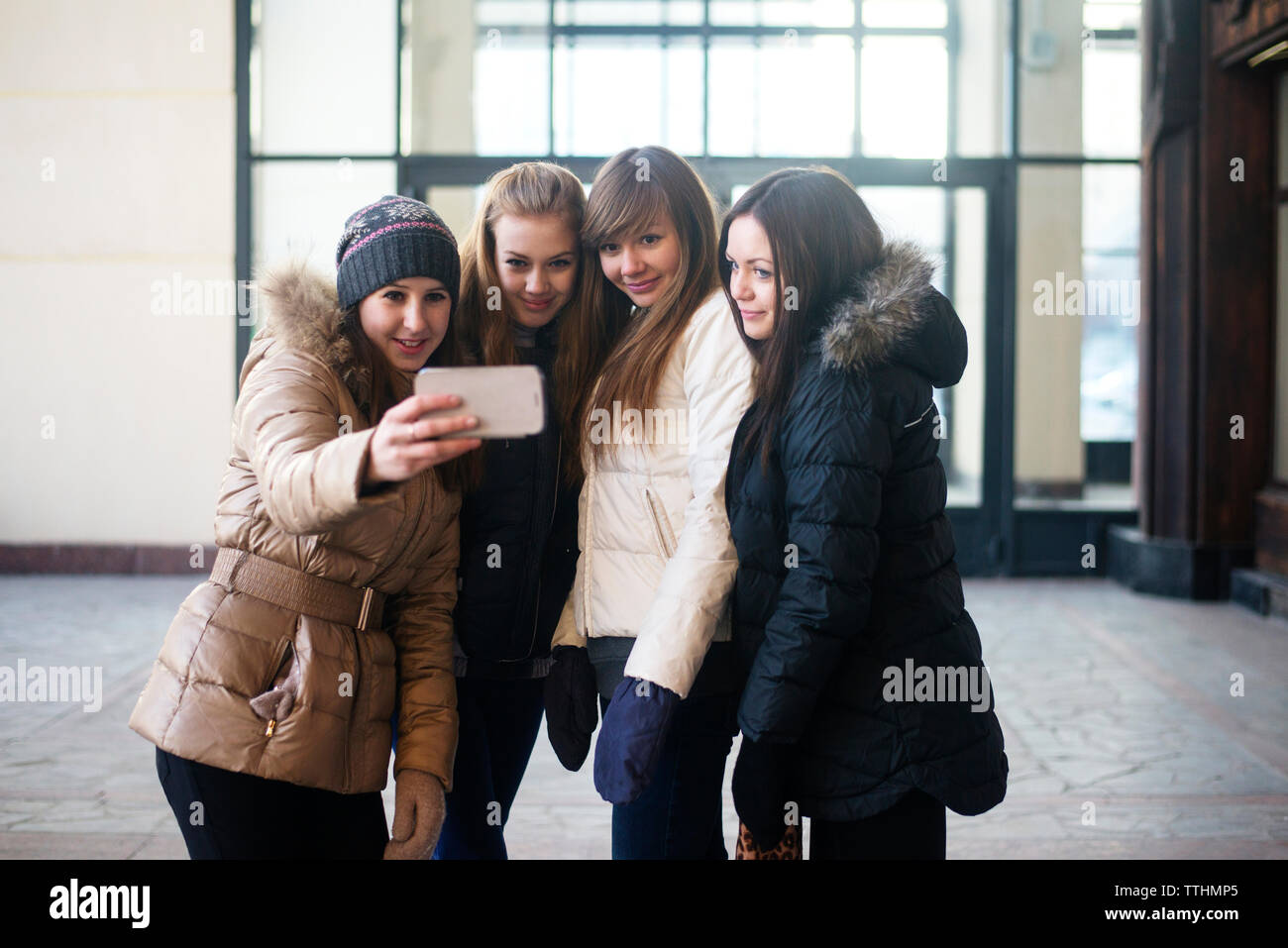 Weibliche Freunde unter selfie durch Smart Phone beim Stehen außerhalb des Gebäudes Stockfoto