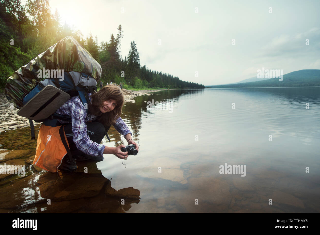 Portrait von weiblichen Wanderer zusammengekauert am See Stockfoto