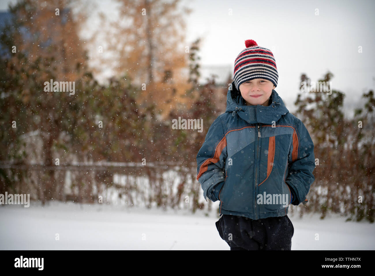 Portrait von lächelnden Jungen in warme Kleidung stehen auf schneebedeckten Feld Stockfoto