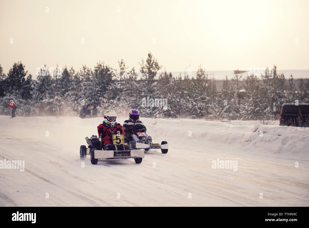 Jungen genießen Go-karts Racing auf schneebedeckten Feld gegen Sky Stockfoto