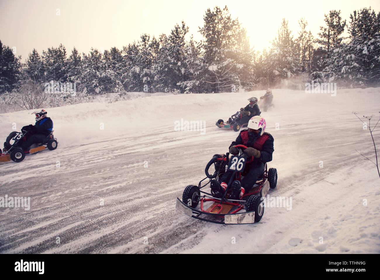 Boys Racing auf Go-carts am schneebedeckten Feld Stockfoto