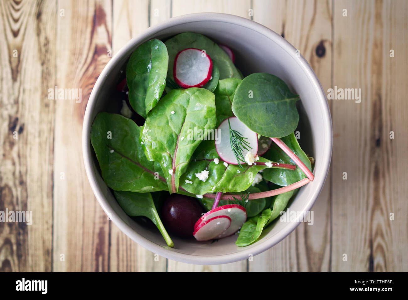 Ansicht von oben von Spinat und Rettich Salat mit Kirschen in der Schüssel auf dem Tisch Stockfoto