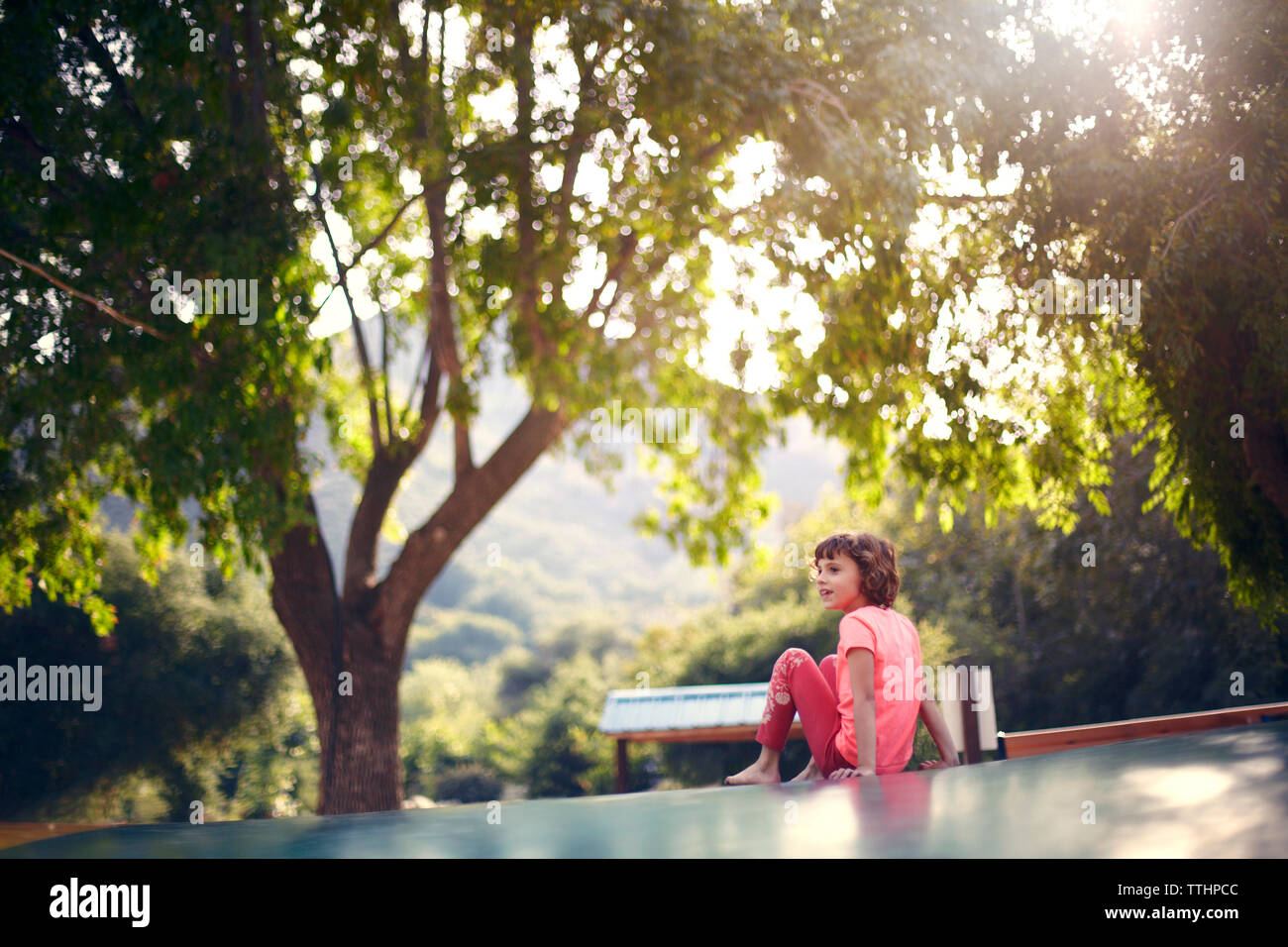 Mädchen sitzen auf Trampolin und Wegsehen Stockfoto