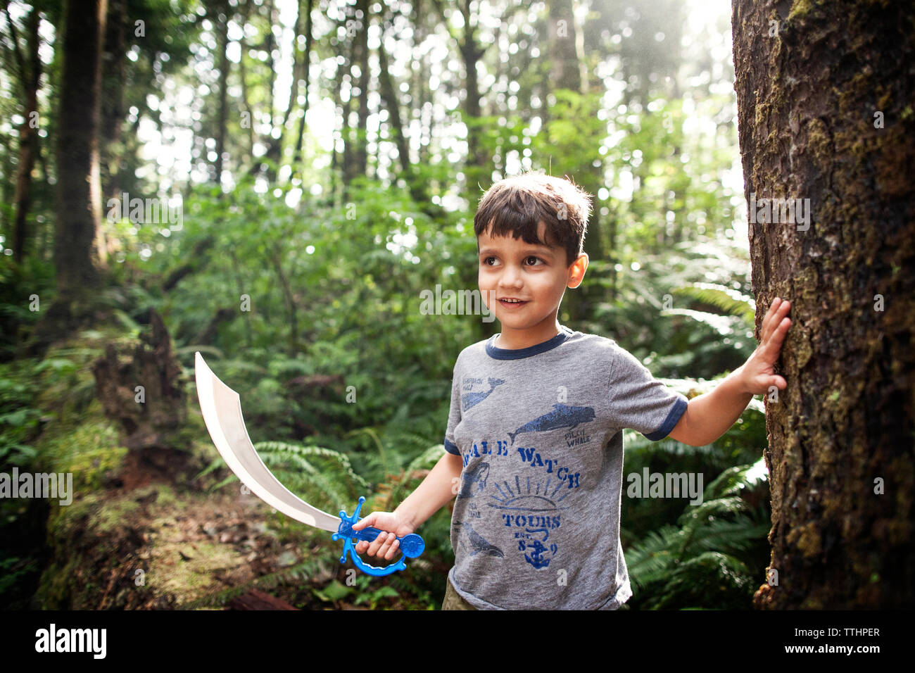 Junge holding Spielzeugschwert beim Stehen in Wald Stockfoto