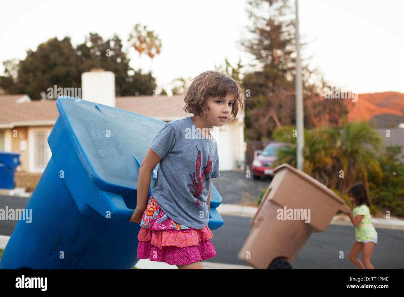 Girl garbage ziehen kann beim Gehen auf der Straße Stockfoto