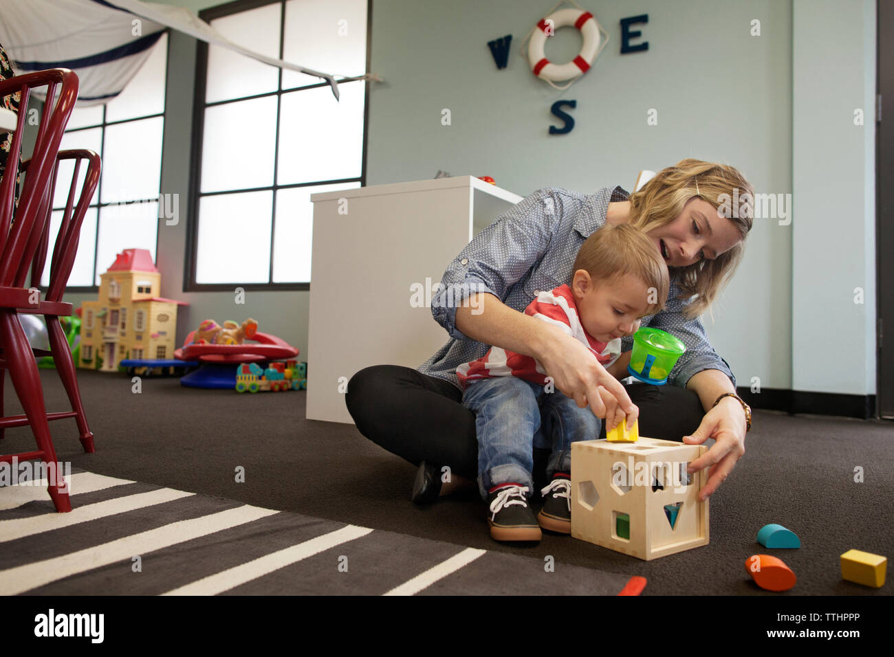 Frau und Junge spielt mit geometrischen Puzzle Box bei Vorschule Stockfoto