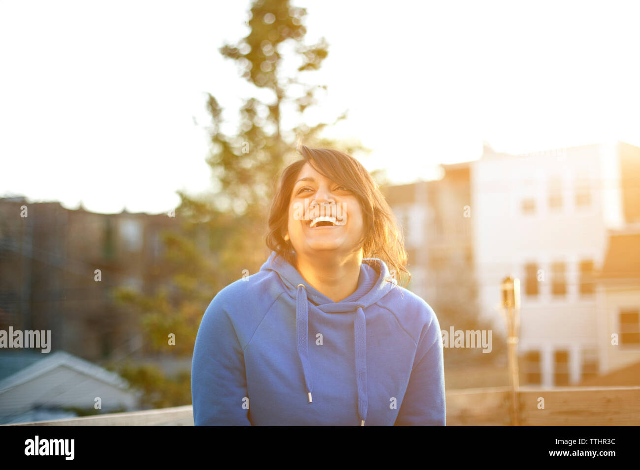 Fröhliche Frau stehend gegen Himmel bei Sonnenuntergang Stockfoto