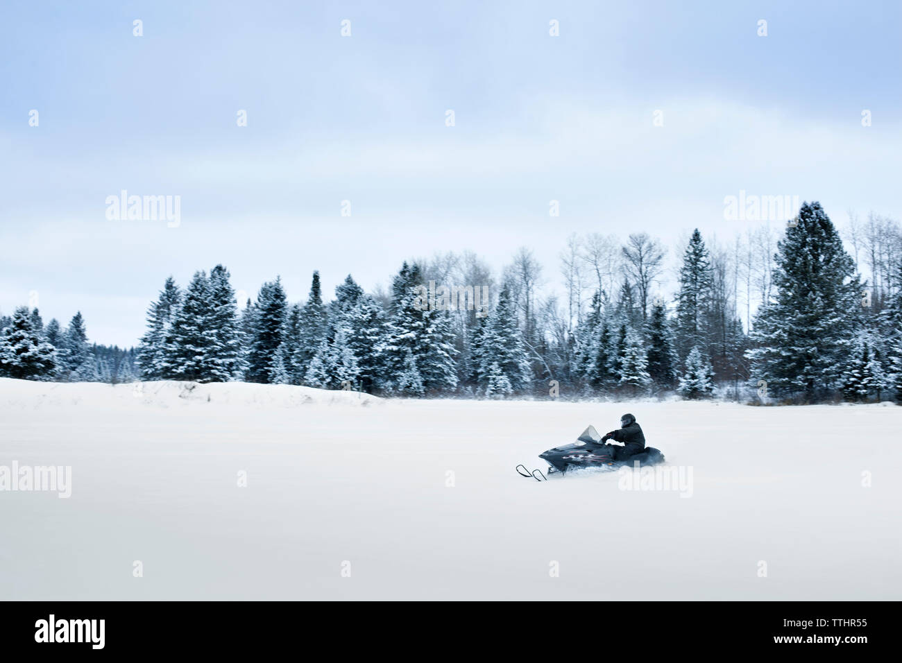 Mann, Schneemobil auf Landschaft gegen Sky Stockfoto