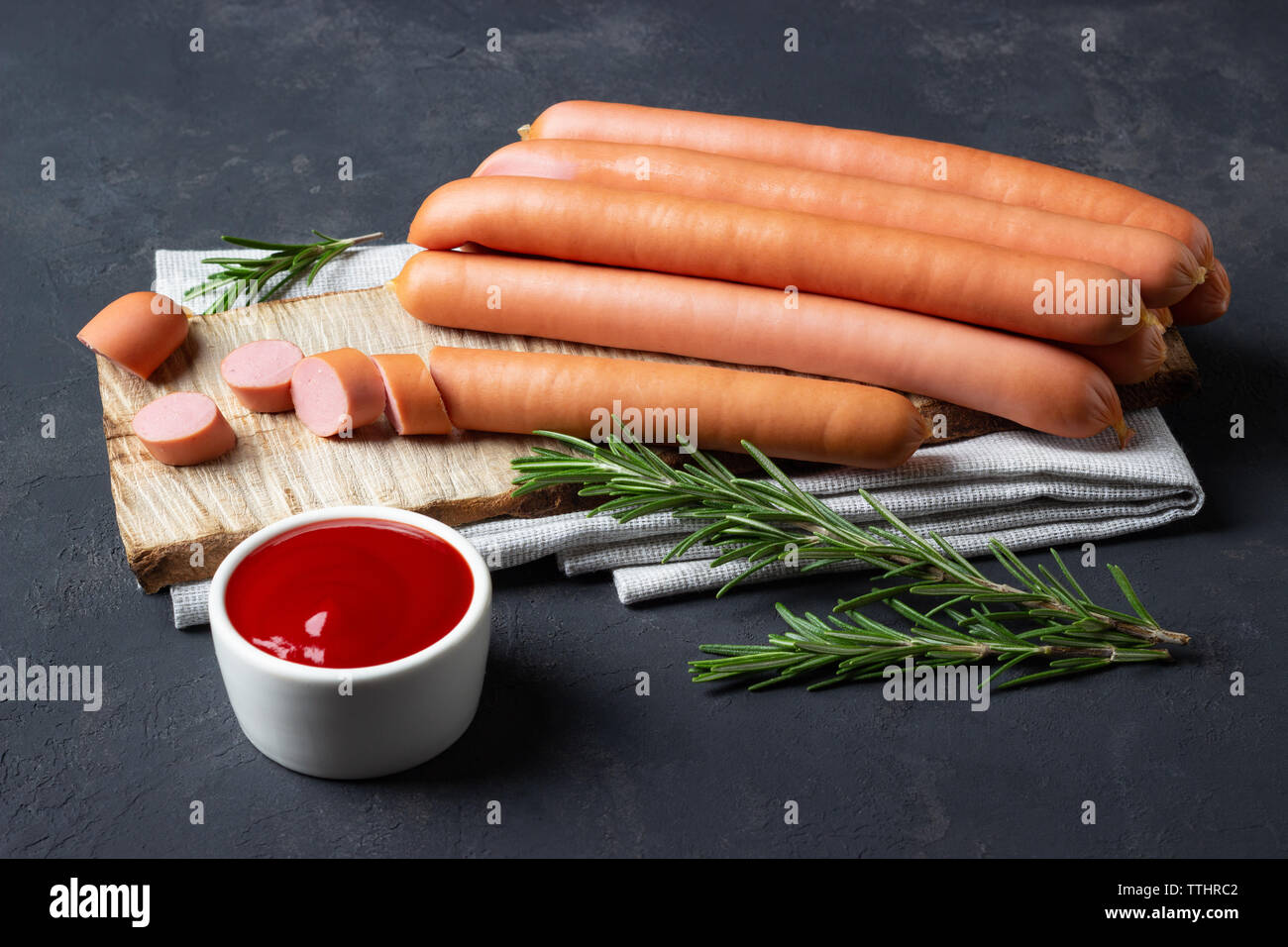 Raw Frankfurter Würstchen mit Ketchup auf Schneidebrett. Stockfoto