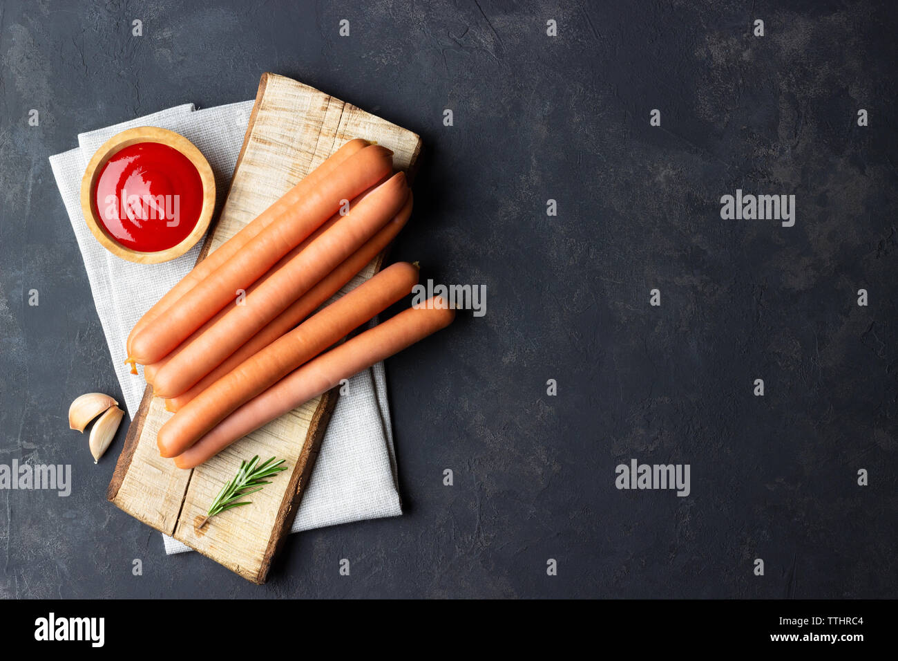 Raw Frankfurter Würstchen mit Ketchup auf Schneidebrett. Ansicht von oben. Kopieren Sie Platz für Text. Stockfoto