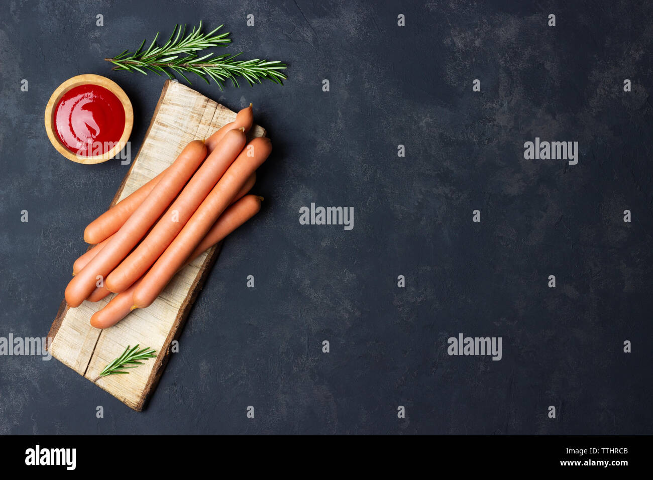 Raw Frankfurter Würstchen mit Ketchup auf Schneidebrett. Ansicht von oben. Kopieren Sie Platz für Text. Stockfoto