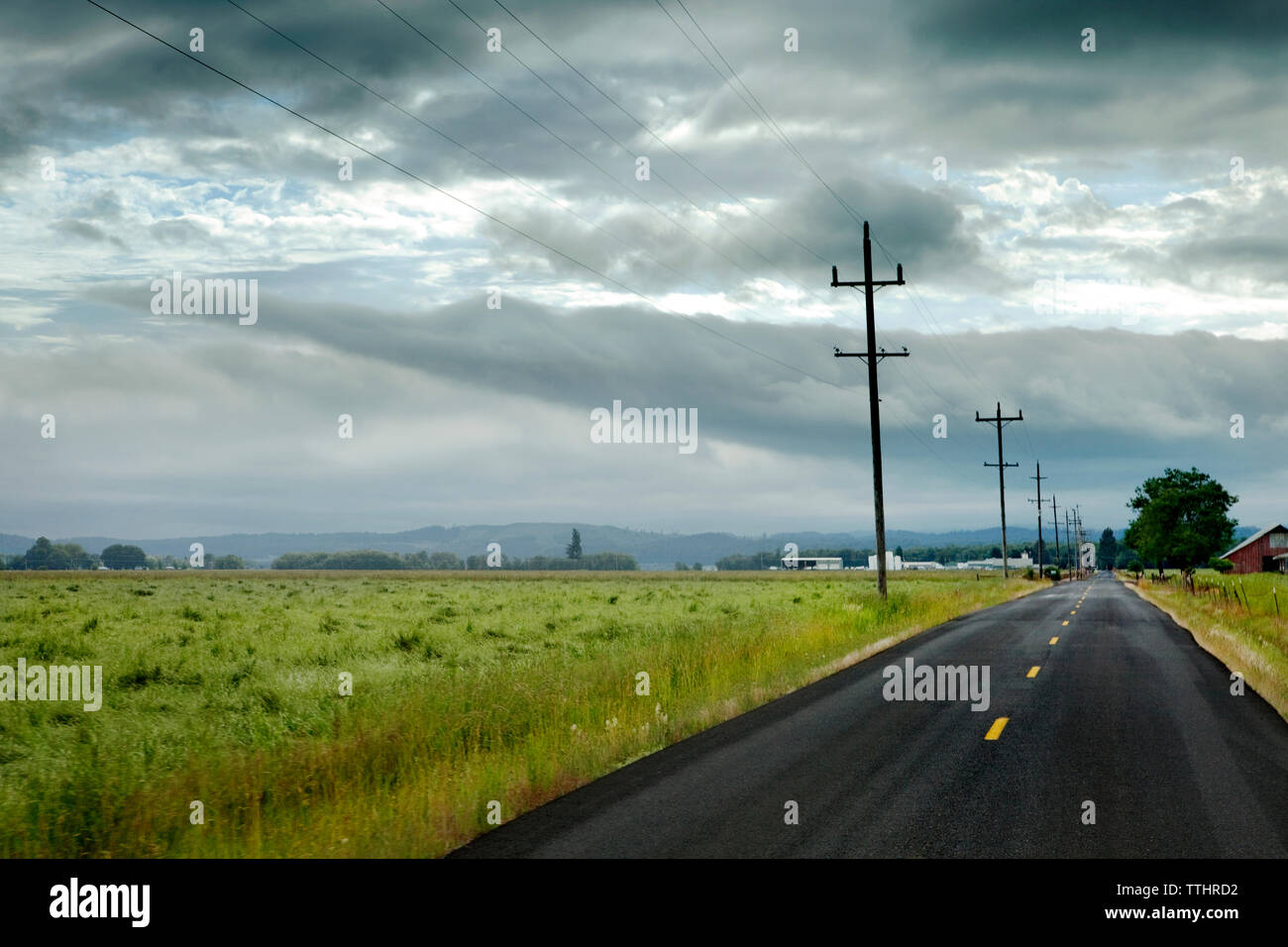 Landstraße von Wiese gegen bewölkter Himmel Stockfoto