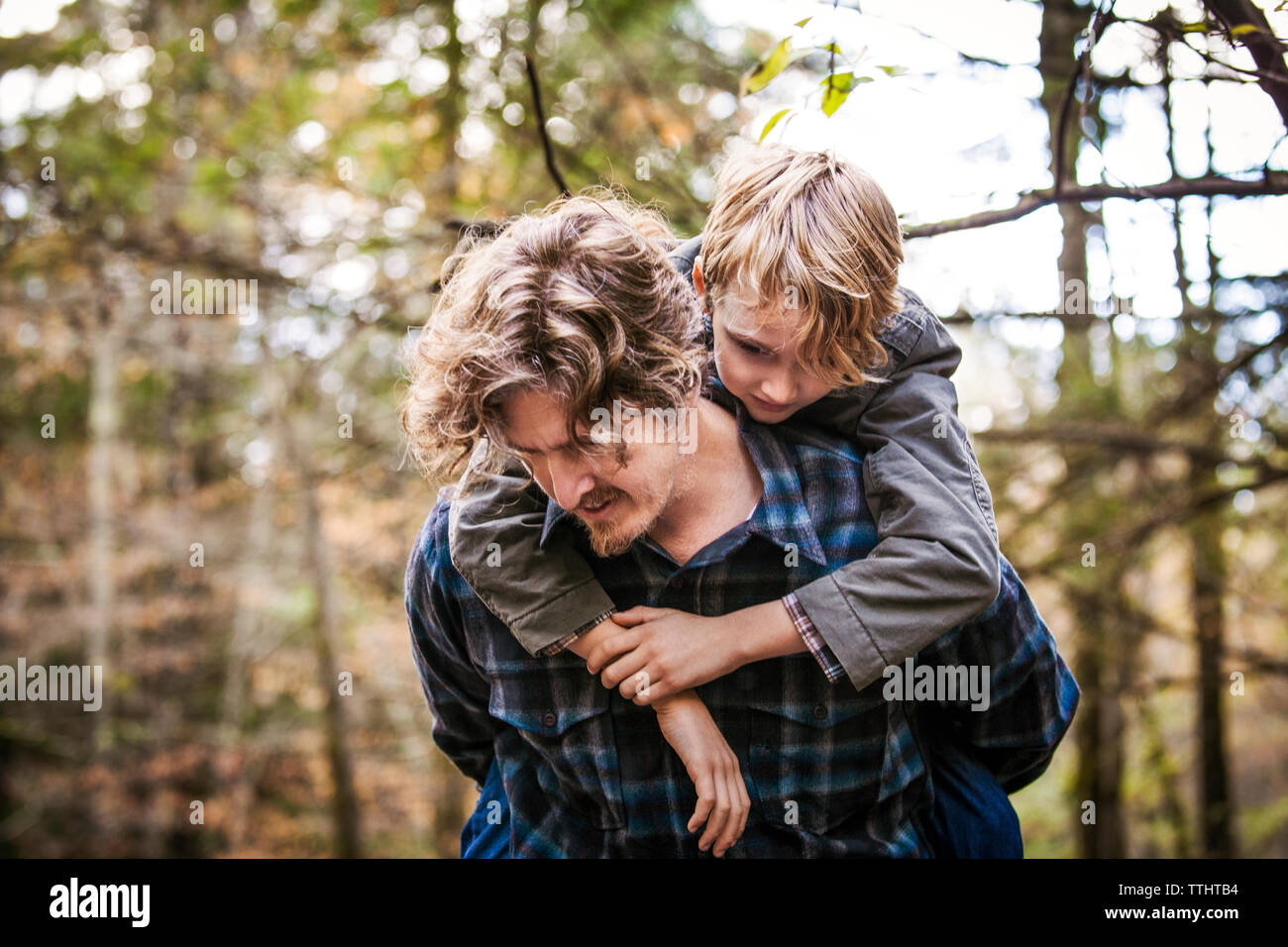 Vater piggyback Ride auf den Sohn im Wald Stockfoto