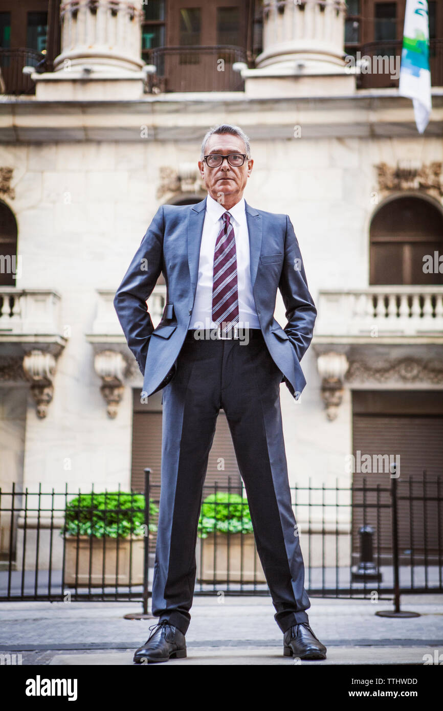 Portrait von älteren Geschäftsmann mit Händen in den Taschen gegen Gebäude Stockfoto