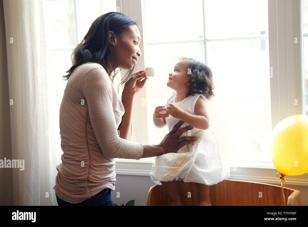 Frau spielt mit Tochter von Fenster zu Hause Stockfoto