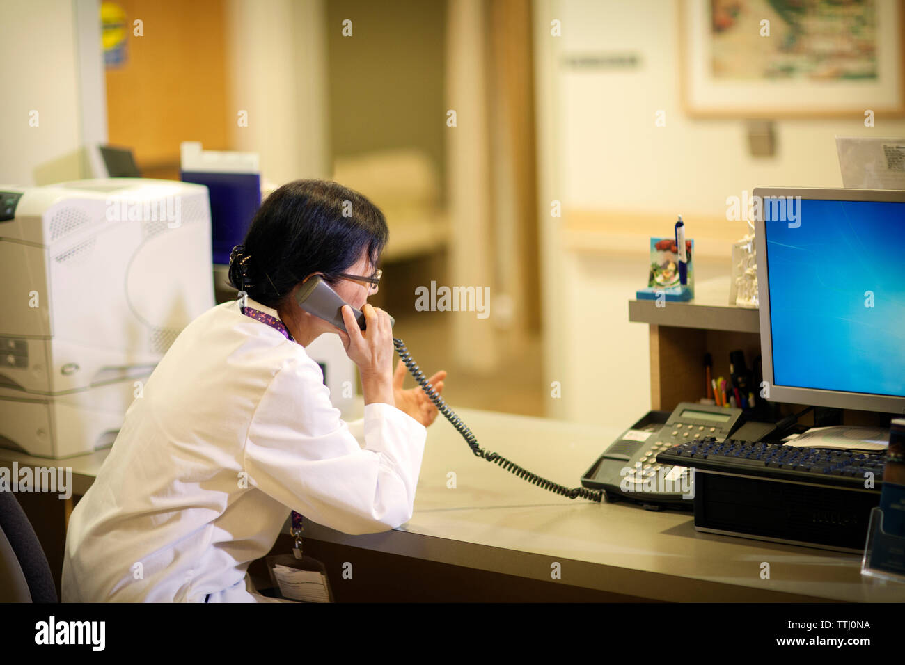 Seitenansicht der Ärztin sprechen über Festnetztelefon im Krankenhaus Stockfoto