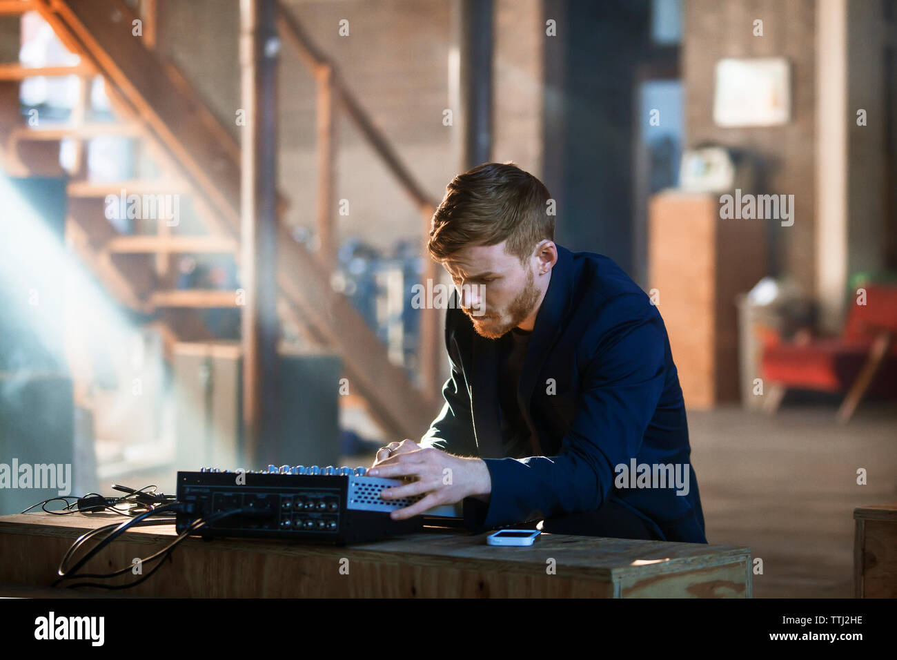 Mann bei der Arbeit auf Audiogeräten während zu Hause sitzen Stockfoto