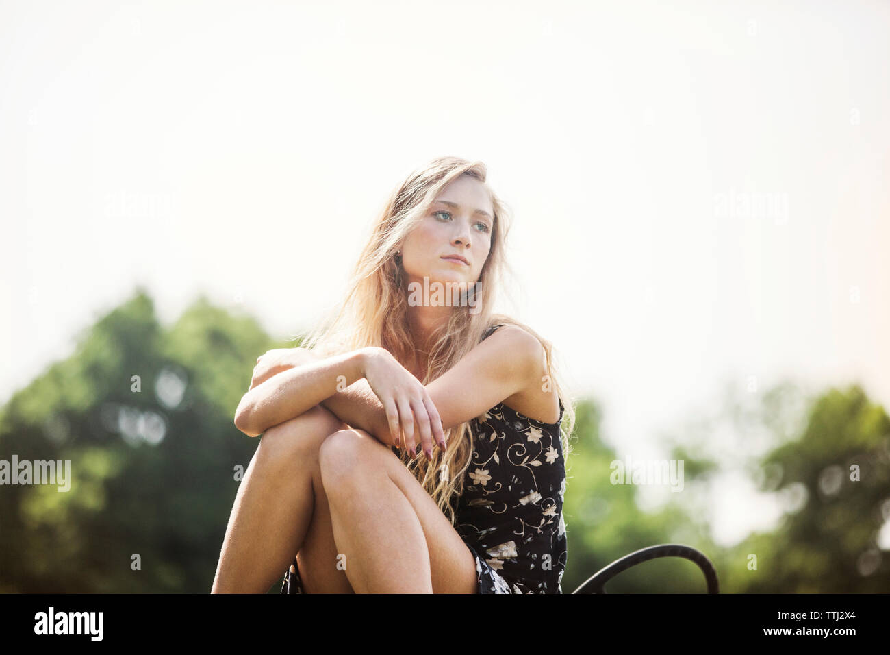 Frau weg, während auf dem Traktor gegen den klaren Himmel sitzen Stockfoto