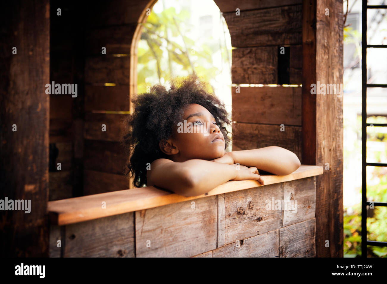 Mädchen in Tree House entfernt und lehnte sich auf Fensterbank Stockfoto