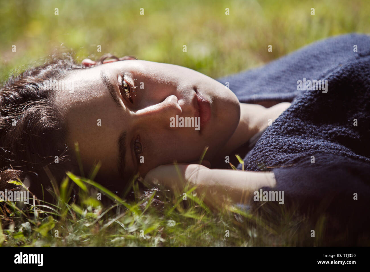 Nachdenklich teenage Mädchen liegt auf Gras Feld Stockfoto