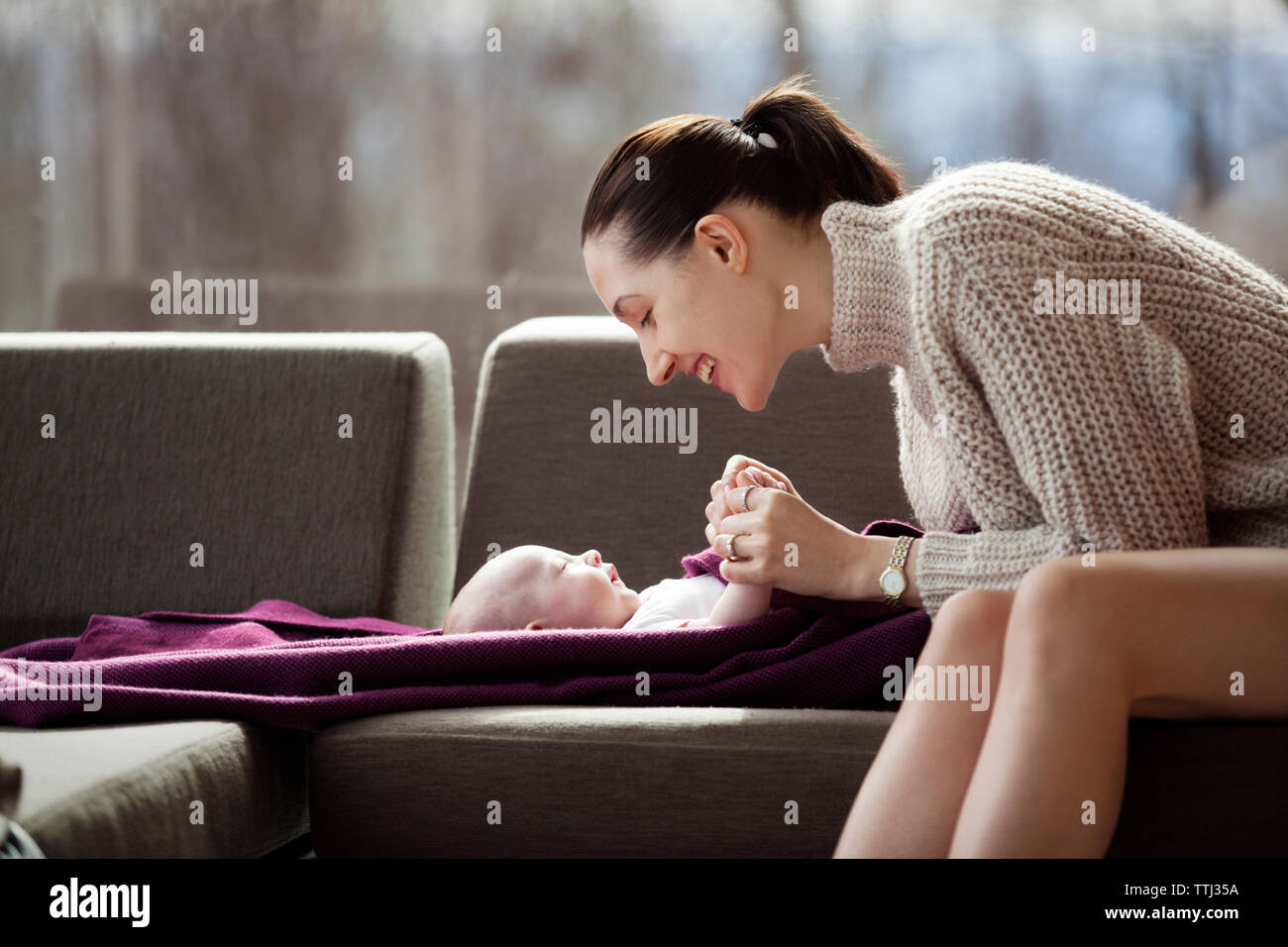 Seitenansicht der glückliche Frau spielt mit Baby Mädchen auf dem Sofa zu Hause Stockfoto