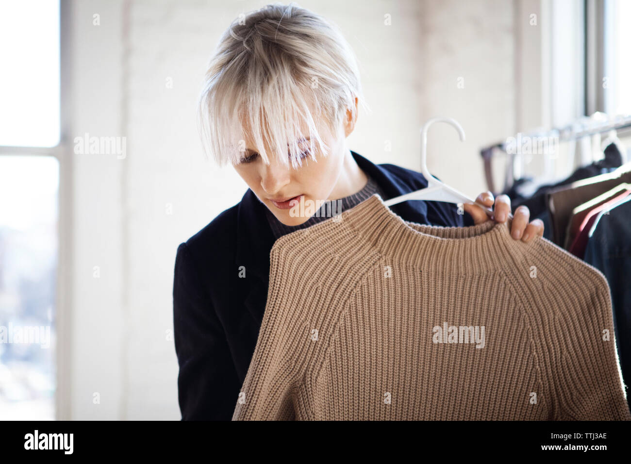 Junge Frau von Pullover bei der Auswahl der Kleidung zu Hause suchen Stockfoto