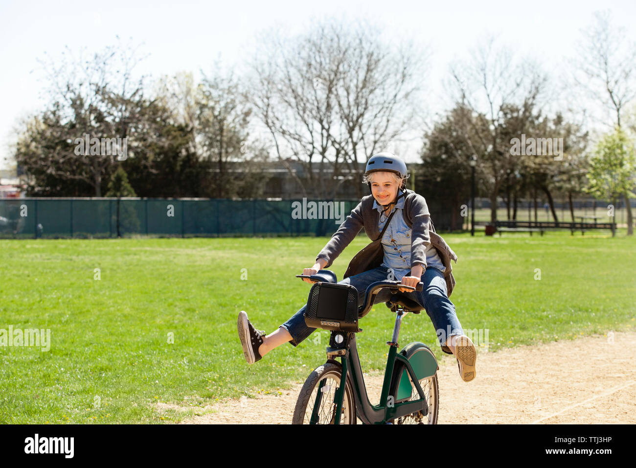 Fröhliche Frau spielen beim Reiten Fahrrad im Park Stockfoto