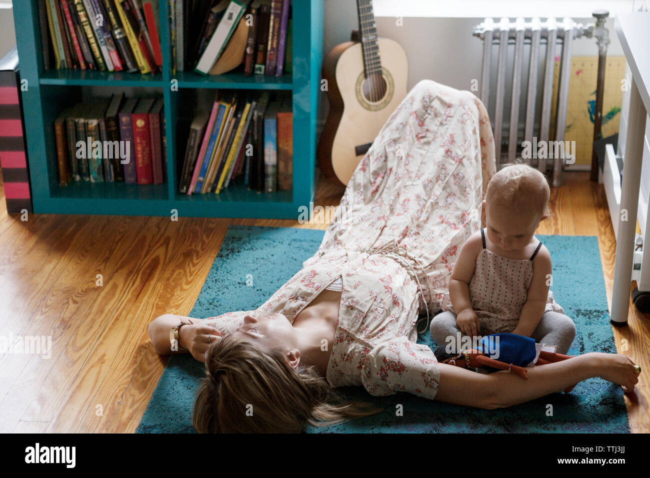 Hohe Betrachtungswinkel der Mutter schlafen, während Baby spielen mit Spielzeug auf dem Teppich Stockfoto