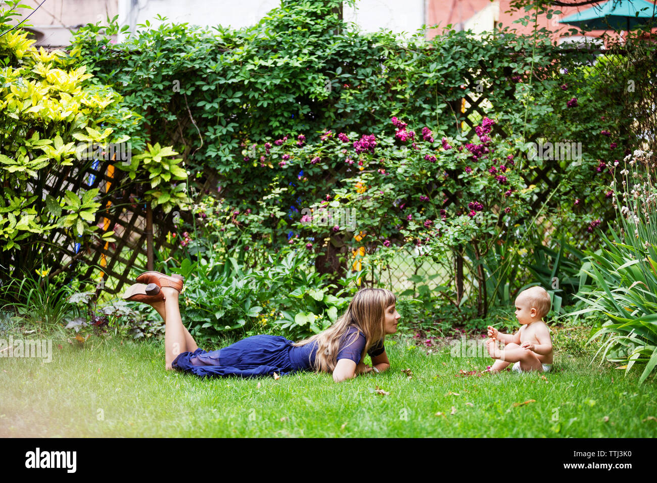 Mutter unten liegen und Baby auf Wiese im Hinterhof Stockfoto