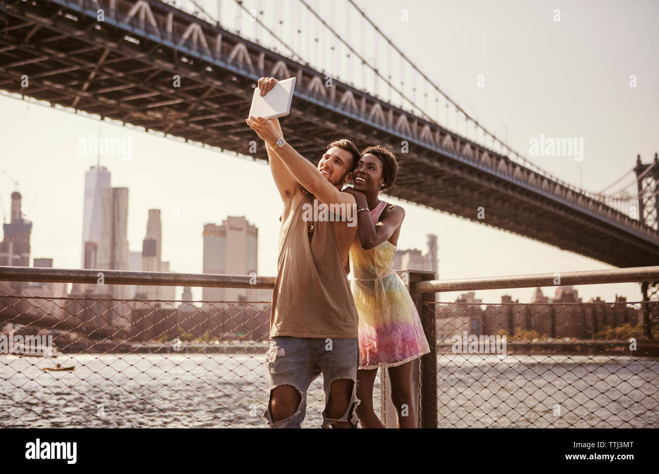 Multi-ethnischen Paar unter selfie durch Tablet Computer vor Manhattan Bridge und die Skyline der Stadt Stockfoto