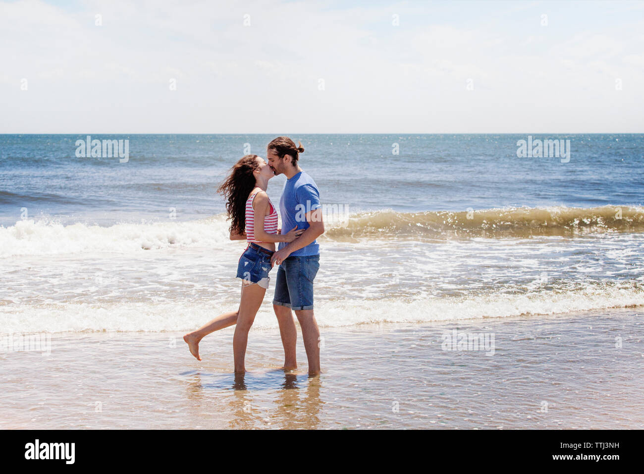 Zärtlich paar Küssen beim Stehen auf Ufer am Strand Stockfoto