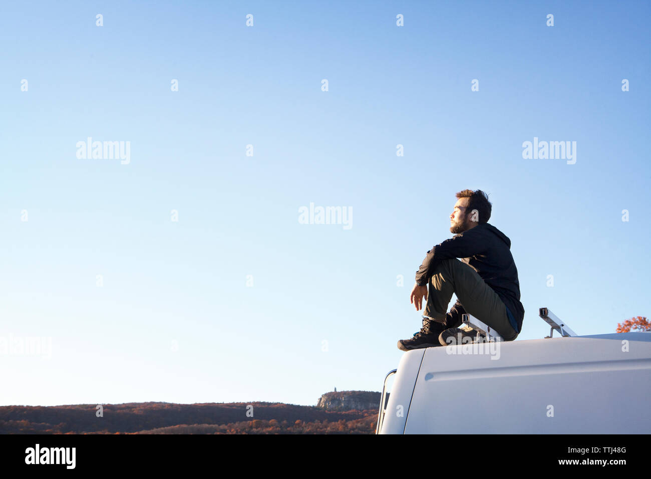 Seitenansicht der Mann sitzt auf Wohnmobil gegen den klaren Himmel Stockfoto