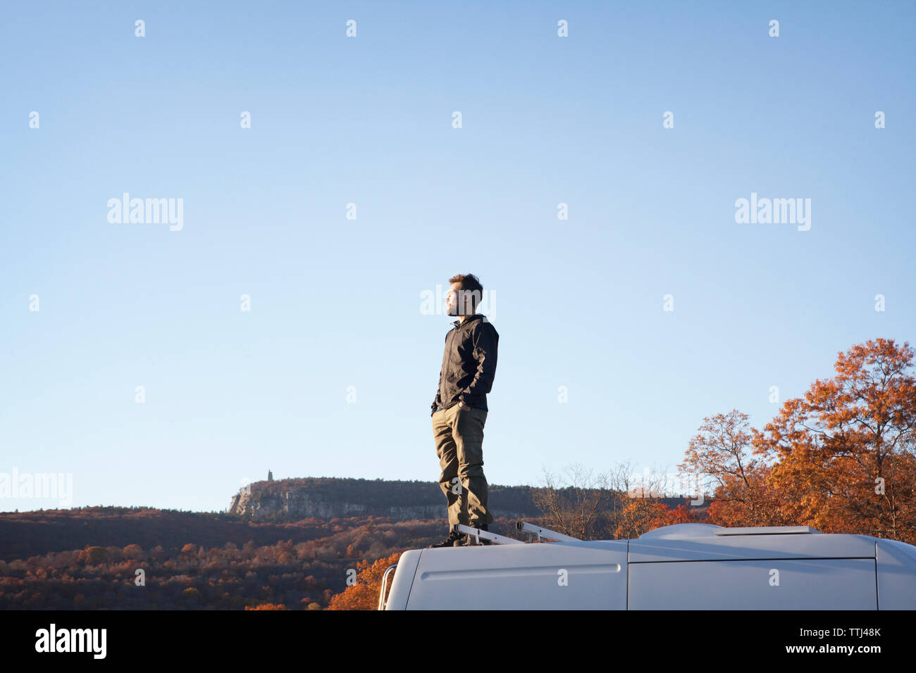 Mann mit den Händen in der Tasche stehen auf Wohnmobil gegen den klaren Himmel Stockfoto