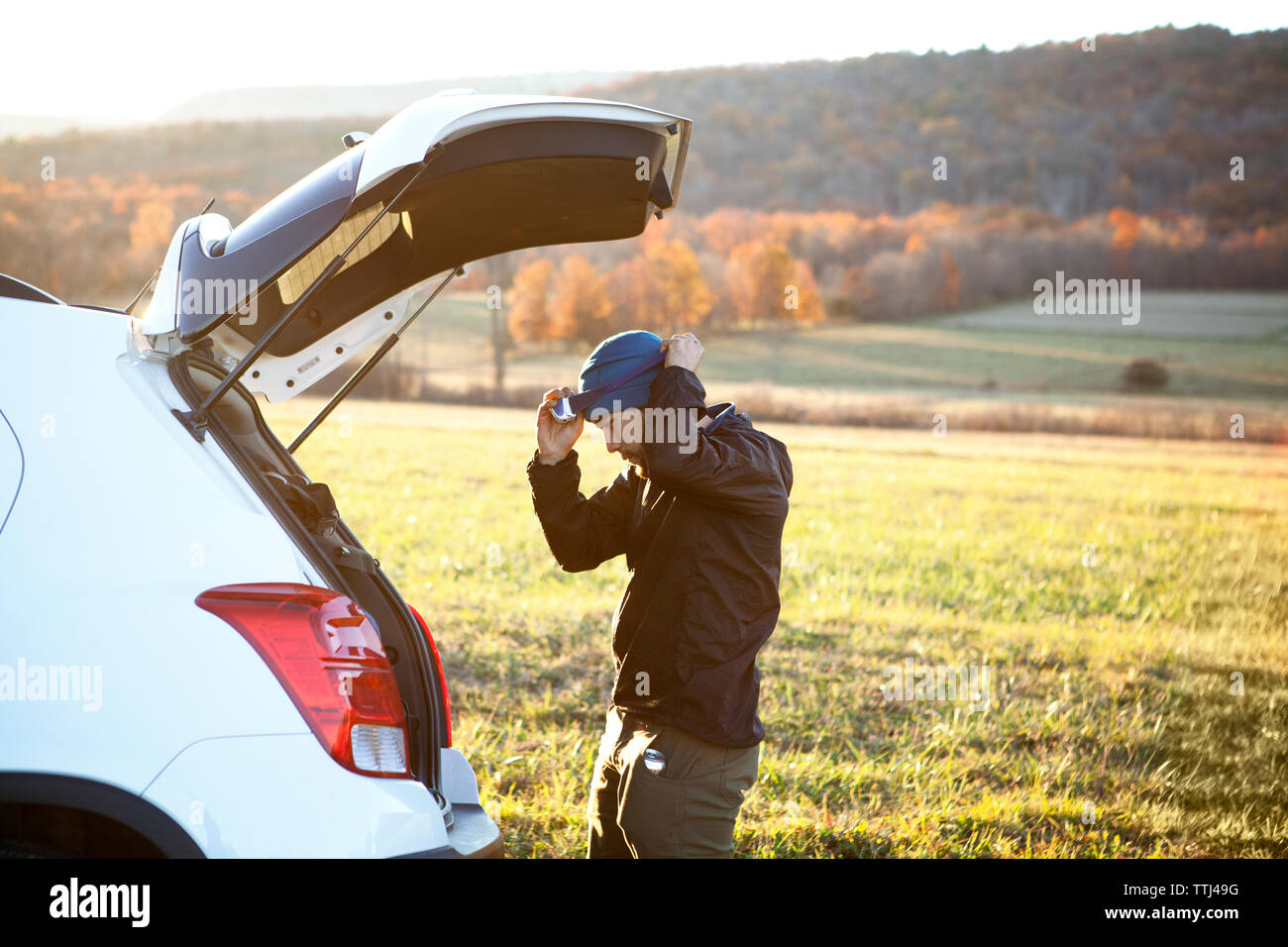Seitenansicht des Menschen Scheinwerfer tragen, während mit dem Auto stehend auf dem Feld Stockfoto