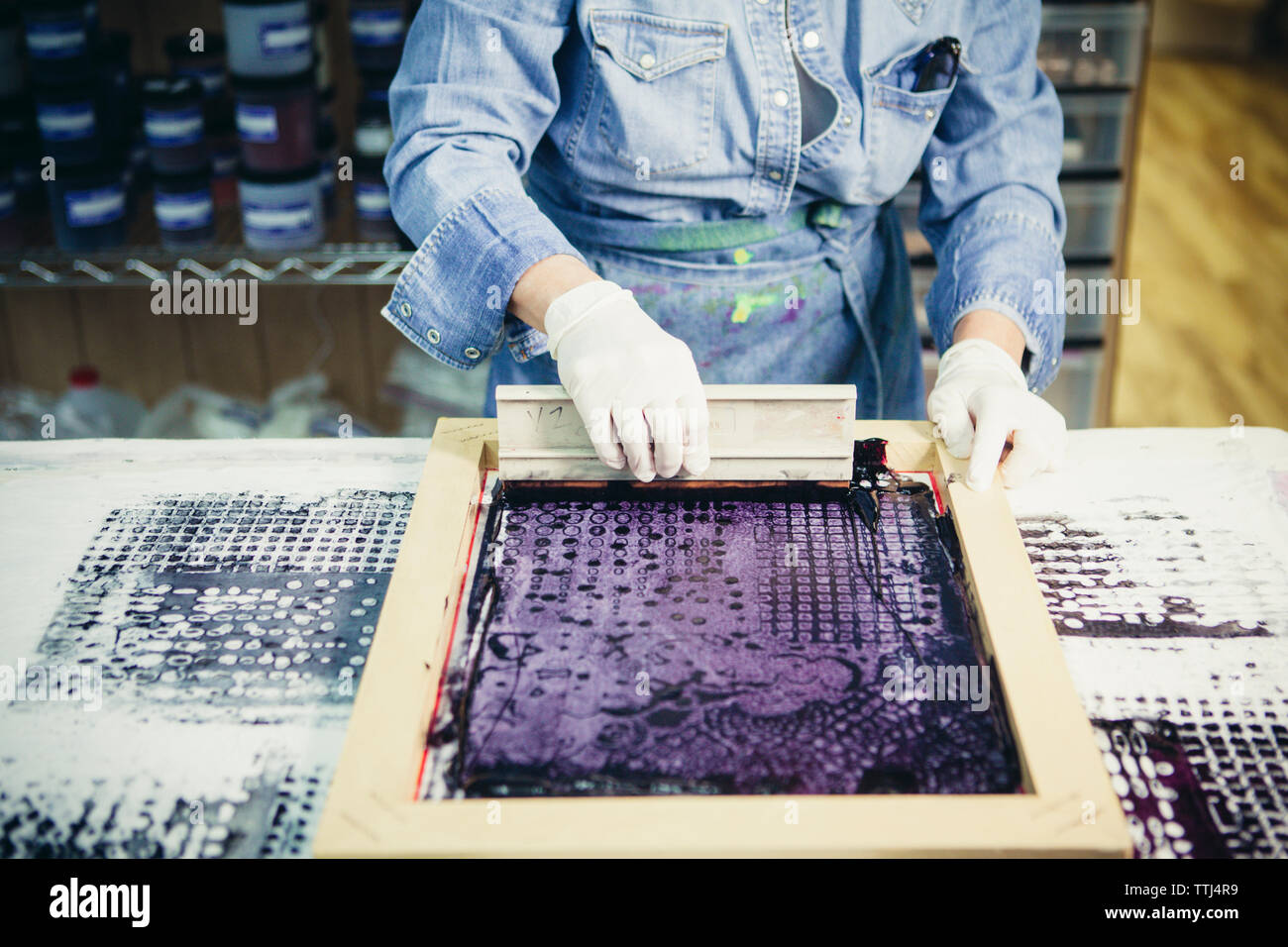 Mittelteil der handwerkerin mit Siebdruck Design auf Gewebe von Werkstatt zu drucken. Stockfoto