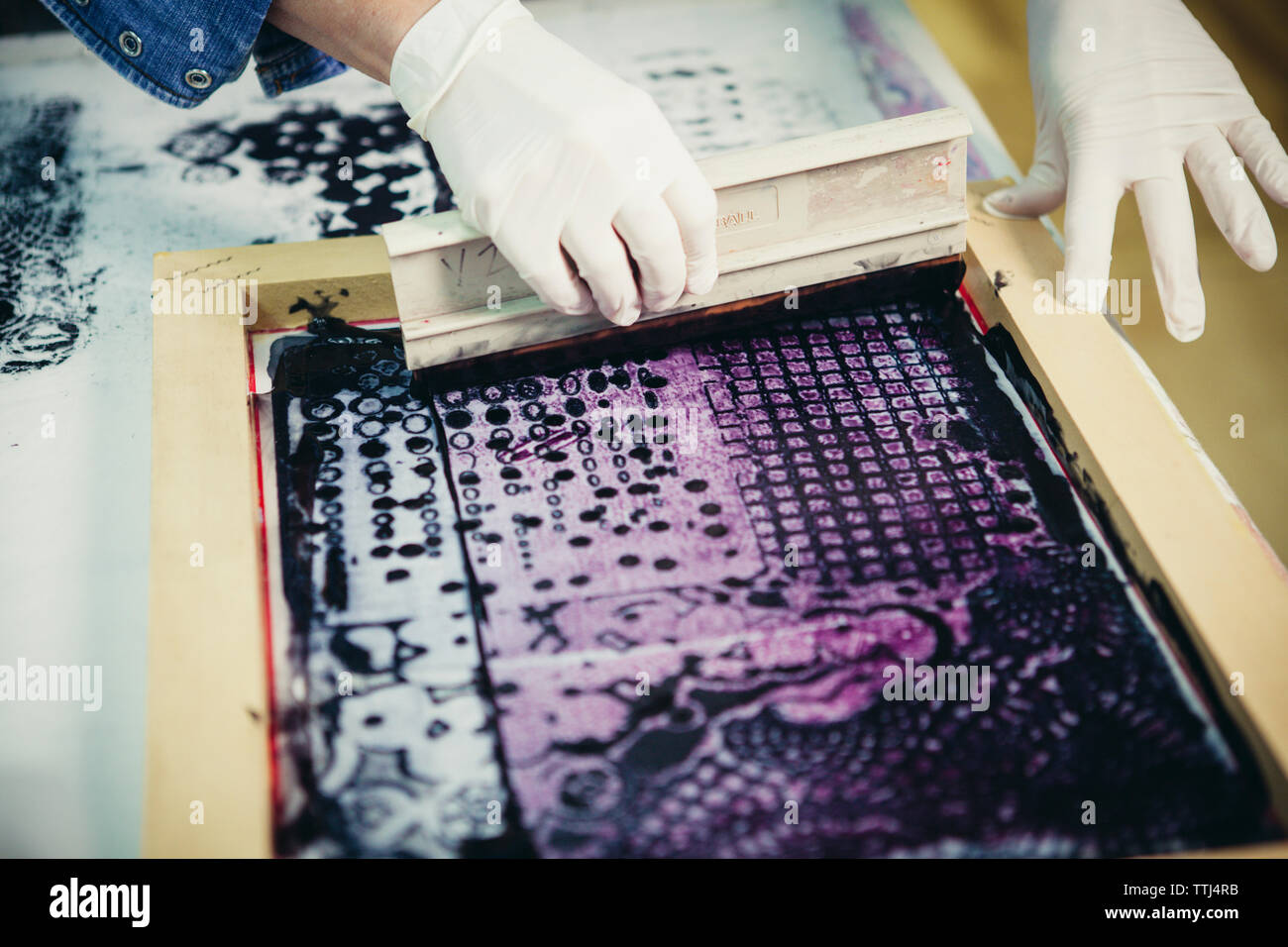 7/8 Hände der handwerkerin mit Siebdruck Design auf Gewebe von Werkstatt zu drucken. Stockfoto
