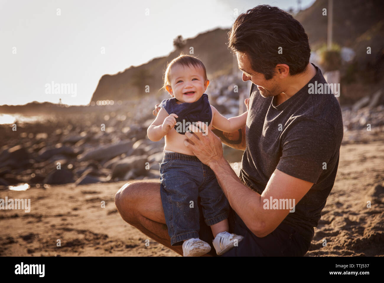 Vater mit fröhlichen Jungen am Strand Stockfoto