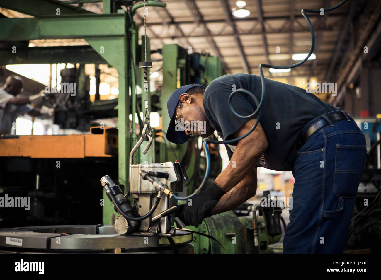 Seitenansicht der Arbeiter mit Maschinen, während in der Metallindustrie arbeiten Stockfoto