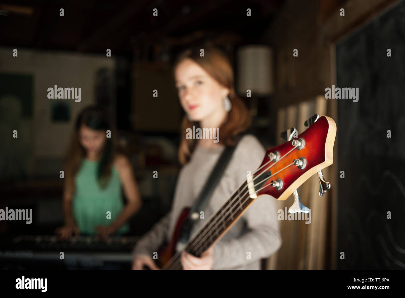 Mädchen mit Gitarre mit Freund im Hintergrund Stockfoto