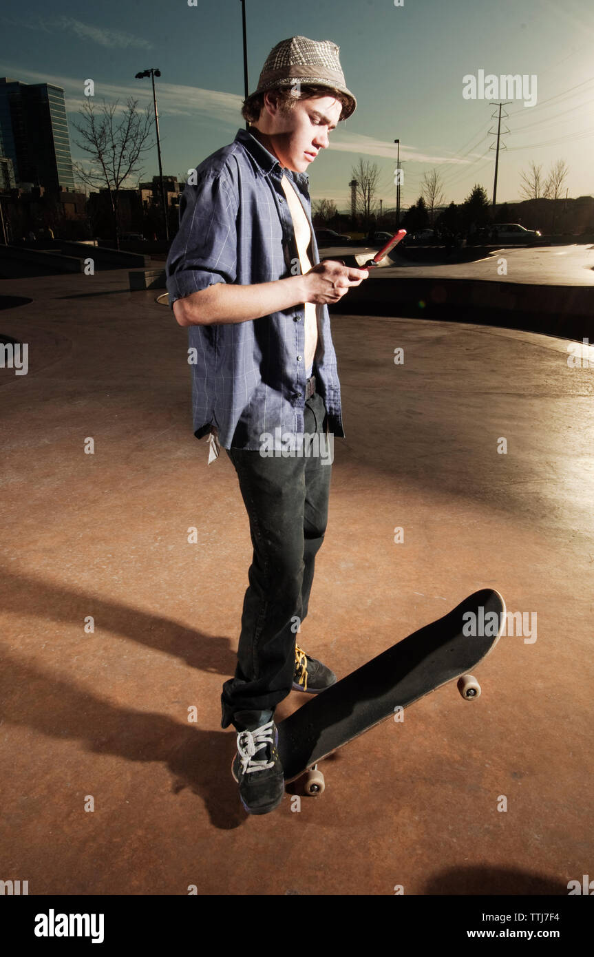 Mit Handy beim Stehen mit Skateboard auf Sport Rampe Mann Stockfoto