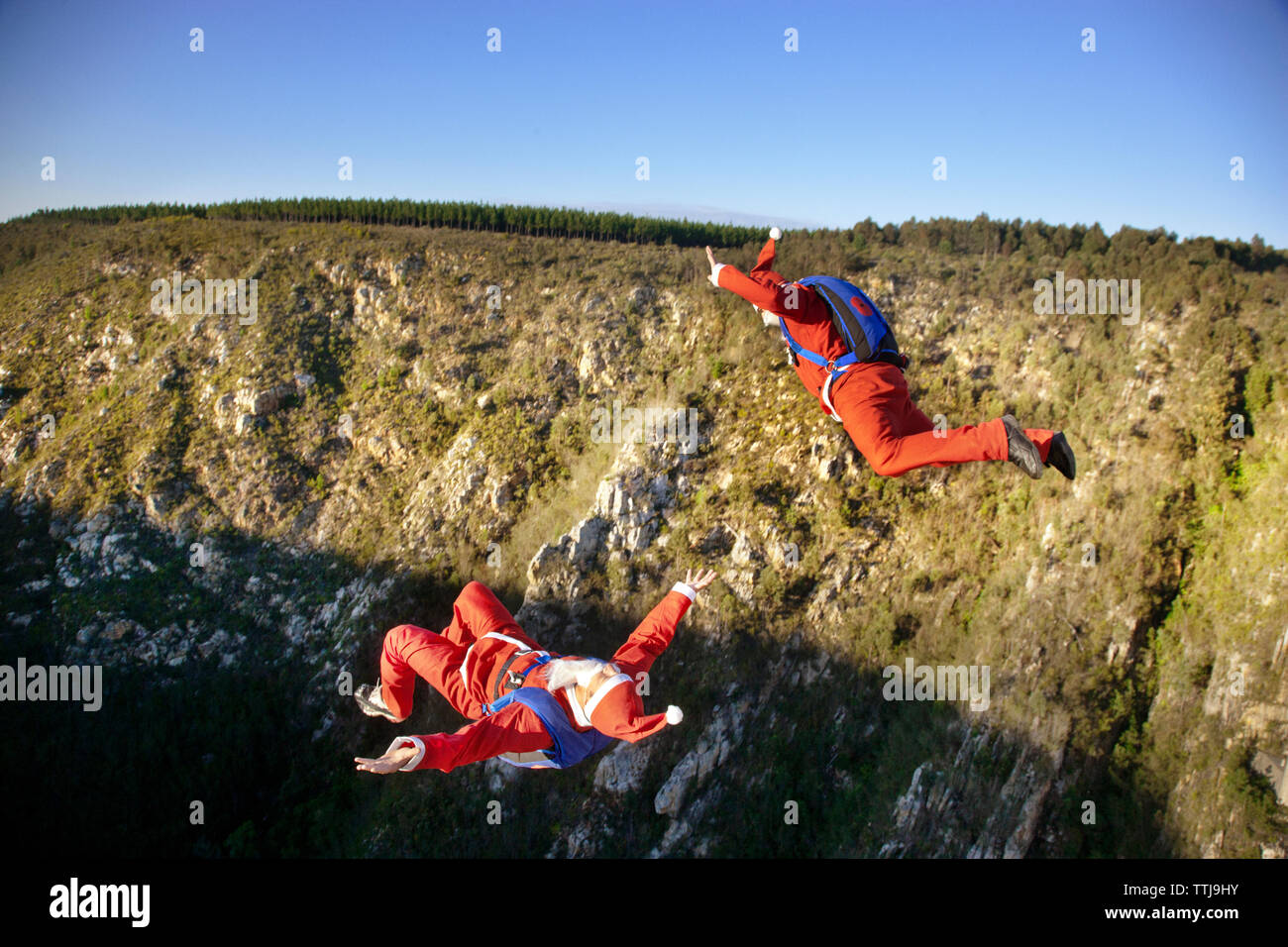 Menschen in Santa Claus kostüm Base Jumping gegen den klaren Himmel Stockfoto