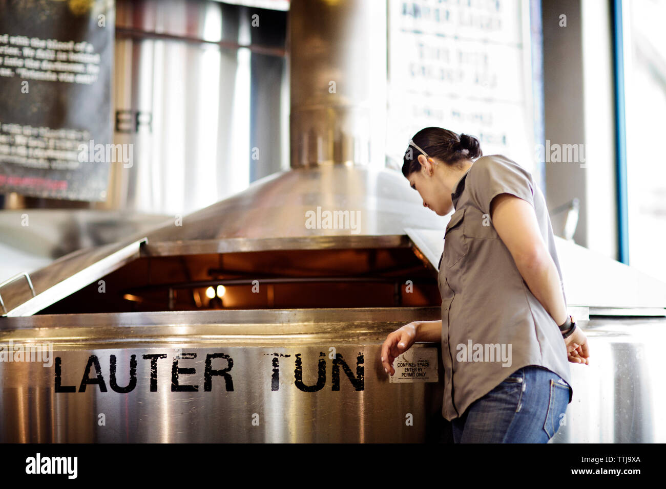 Frau Prüfung Bier in Storage tank beim Stehen an der Brauerei Stockfoto